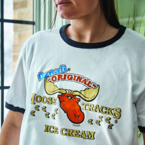 white t-shirt with black ringer banding around neck and arms. features moose tracks ice cream logo