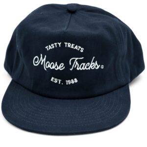 A front view of the Moose Tracks Navy Snapback Hat placed on a flat surface. The hat is navy with white-colored embroidered text reading "Tasty Treats Moose Tracks EST. 1988".